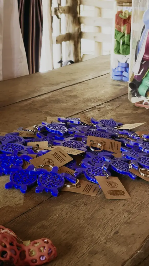 Chaveiros azuis em forma de tartaruga feitos de tampinhas plásticas recicladas