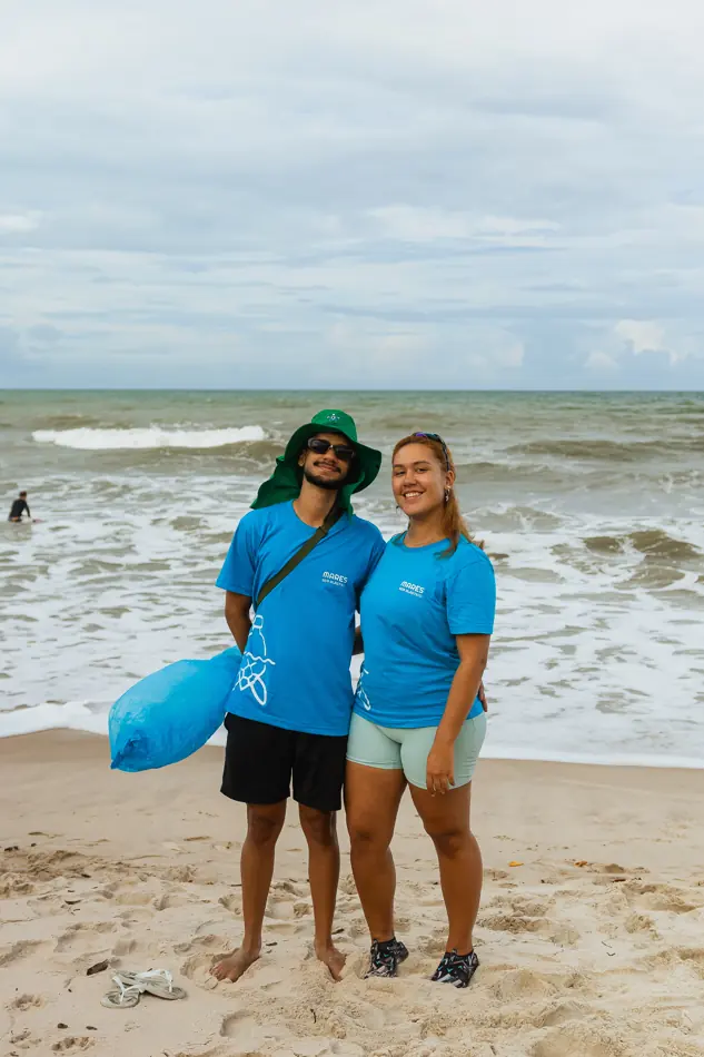 Duas voluntárias na praia com sacos de coleta